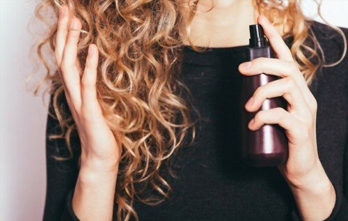woman using hair serum on ends of hair
